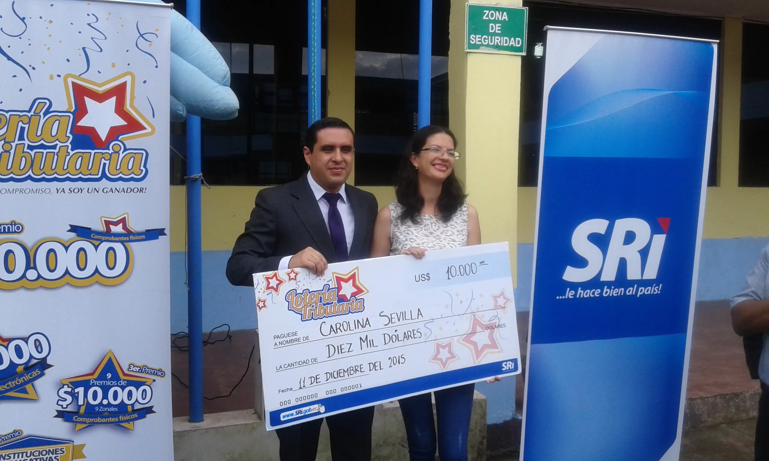 Junto al cheque de entrega carolina Sevilla y el director del SRI